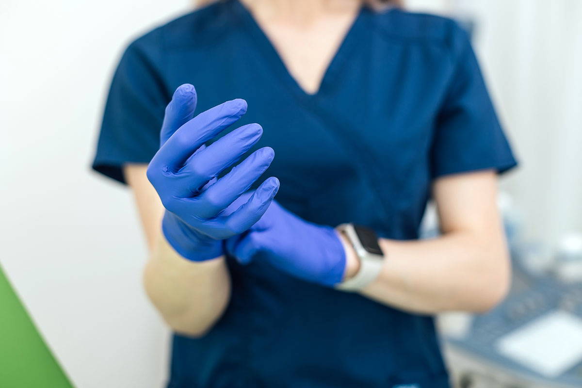 Doctor putting on blue gloves. Gloves for Care Home Workers